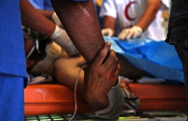 A fighter grasps a doctors arm inside a field hospital on the western frontline of Misrata. Photo by Rachel Beth Anderson.