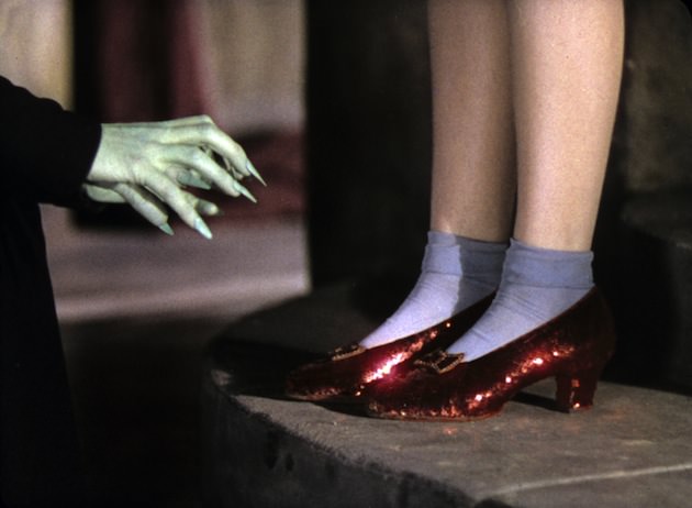 Dorothy (Judy Garland) wore the most famous shoes in the world. Costume designer Adrian. "It's unknown how many pairs of the shoes were made, but it's believed four pairs used in the film still exist today. The surviving pairs were made in sizes 5C, 5.5 and 6B to accommodate Judy Garland, her stand in and stunt double. The slippers began as white silk pumps made by the Innes Shoe Company in Los Angeles, and they were later dyed red at MGM Studios before being covered with fabric that had been hand-sewn with approximately 2,300 sequins. Each red leather bow, designed especially by Adrian, sparkles with red glass stones and bugle beads." Courtesy 'Hollywood Costume' exhibit. 