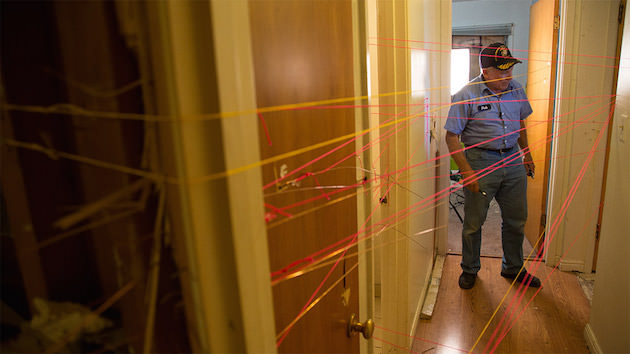 Dub at work piecing together the flight path of bullets at the scene of raid. Courtesy 'Peace Officer.'