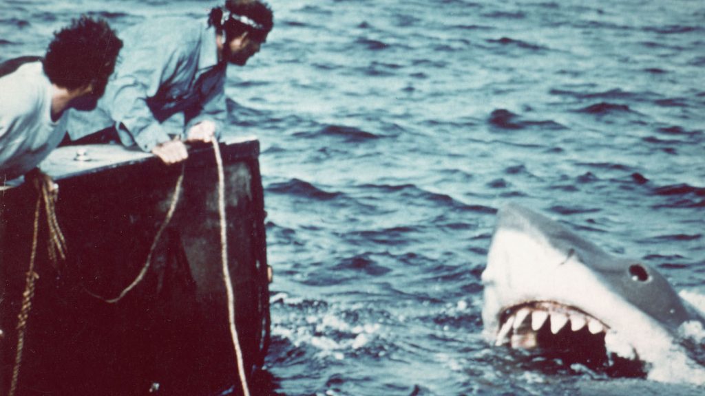 American actor Richard Dreyfuss (left) (as marine biologist Hooper) and British author and actor Robert Shaw (as shark fisherman Quint) look off the stern of Quint's fishing boat the 'Orca' at the terrifying approach of the mechanical giant shark dubbed 'Bruce' in a scene from the film 'Jaws' directed by Steven Spielberg, 1975. The movie, also starring Roy Scheider and Lorraine Gary, was one of the first 'Summer Blockbuster' films. (Photo by Universal Pictures courtesy of Getty Images)