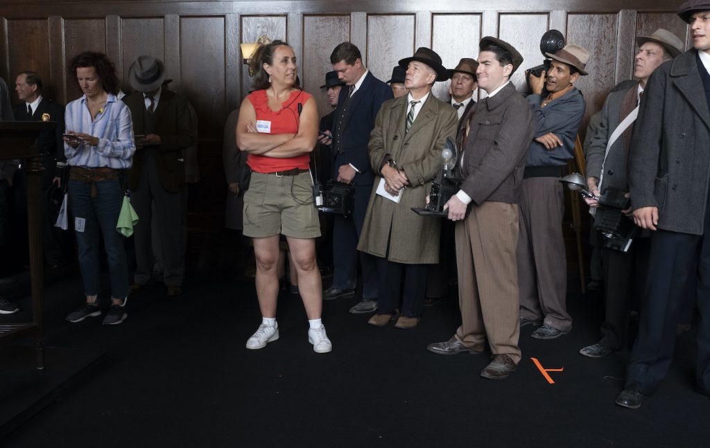 2ND 2ND Asst Director Mollie Stallman has one last look at her background cast of news reporters and photographers in the Courtroom set on Paramount’s Stage 27. Photo by Merrick Morton/HBO. 