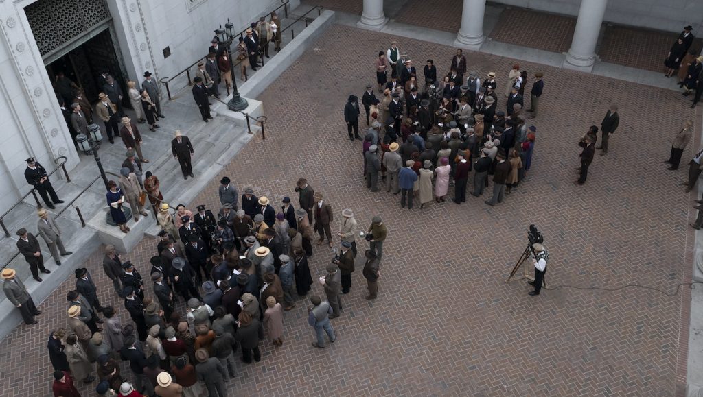 Matthew Rhys (Perry Mason) and Della Street (Juliet Rylance) are surrounded by a variety of background cast, portraying press, police and other onlookers, after the verdict is read in the show’s season finale. Photo by Merrick Morton/HBO