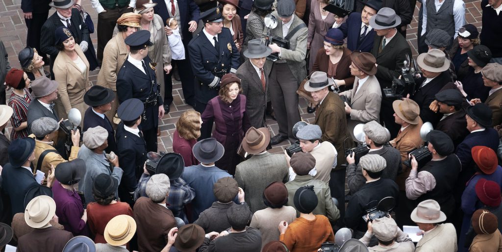 Matthew Rhys (Perry Mason) and Della Street (Juliet Rylance) are surrounded by a variety of background cast, portraying press, police and other onlookers, after the verdict is read in the show’s season finale 