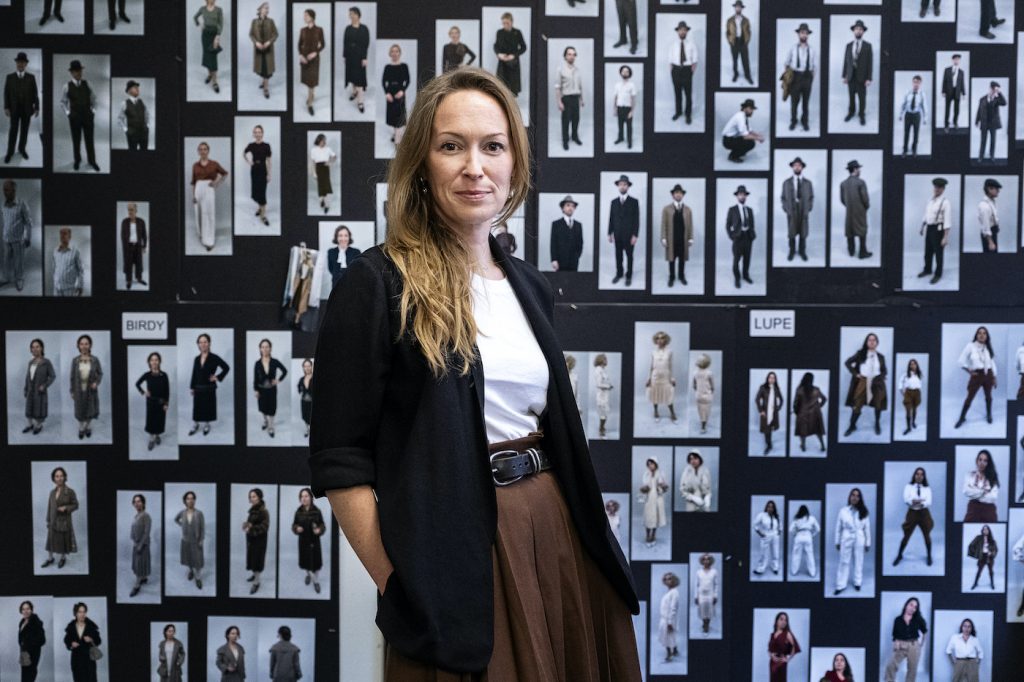 Costume Designer Emma Potter in front of setup boards displaying costume designs for various characters, for easy review and repeat setup. Courtesy HBO.