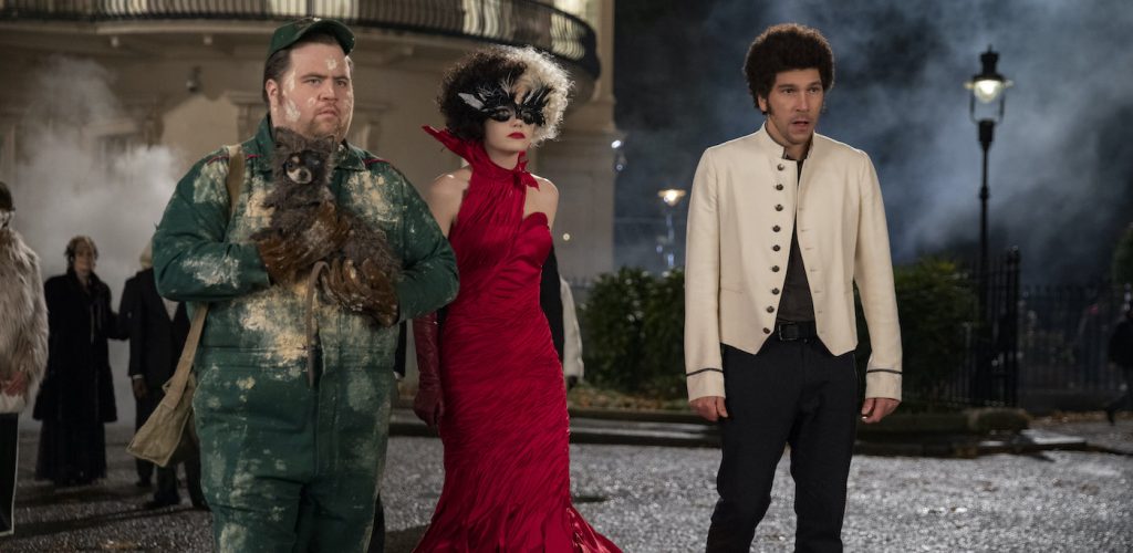 (L-R): Paul Walter Hauser as Horace, Emma Stone as Cruella and Joel Fry as Jasper in Disney’s live-action CRUELLA. Photo by Laurie Sparham. © 2021 Disney Enterprises Inc. All Rights Reserved.