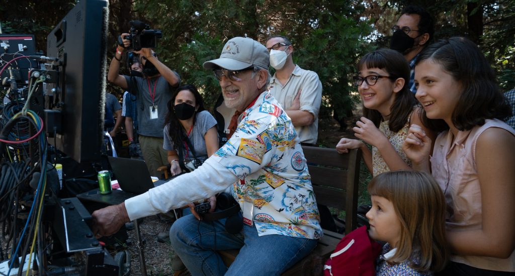 (from left background) Producer Kristie Macosko Krieger, co-writer/producer/director Steven Spielberg, Seth Rogen, Julia Butters, co-writer/producer Tony Kushner, Keeley Karsten and Sophia Kopera on the set of The Fabelmans.